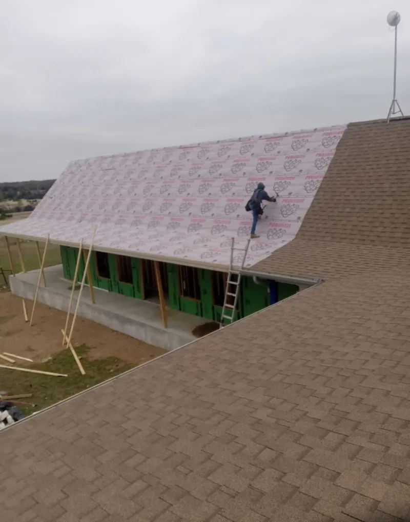 Worker preparing underlayment for a metal roof installation in Wichita